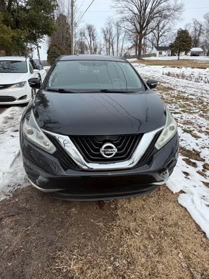 Black Nissan SUV, front view, parked on snowy grass