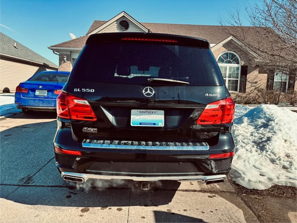 Black Mercedes-Benz GL550 SUV seen from behind in a snowy driveway